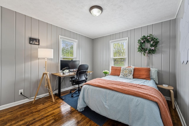 bedroom featuring crown molding, baseboards, wood-type flooring, and a textured ceiling