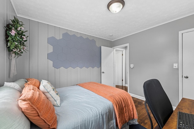 bedroom featuring baseboards, ornamental molding, a textured ceiling, and wood finished floors