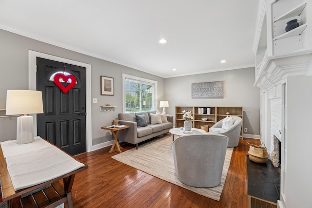 living area with baseboards, ornamental molding, wood finished floors, and a fireplace