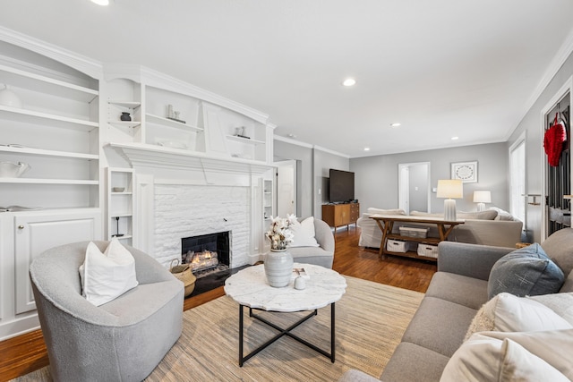 living area with recessed lighting, ornamental molding, wood finished floors, and a fireplace