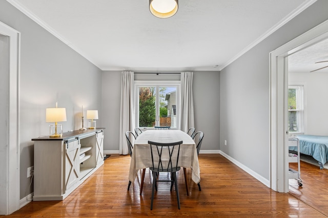 dining area with light wood-type flooring, ornamental molding, baseboards, and a healthy amount of sunlight