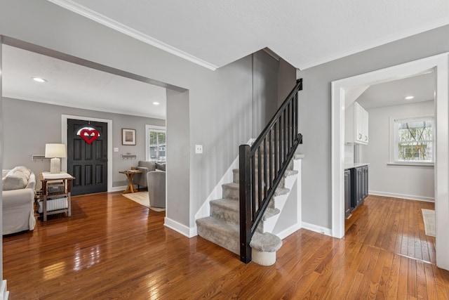staircase featuring ornamental molding, a wealth of natural light, and hardwood / wood-style flooring