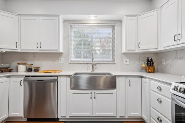 kitchen with decorative backsplash, light countertops, white cabinets, a sink, and stainless steel appliances