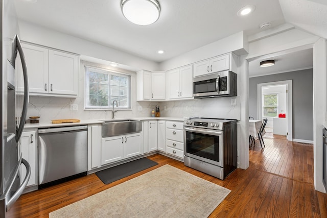 kitchen featuring a sink, backsplash, white cabinets, and stainless steel appliances