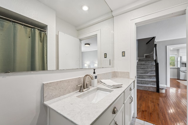 bathroom with recessed lighting, vanity, baseboards, and hardwood / wood-style flooring