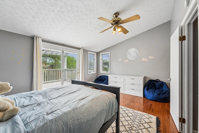 bedroom featuring a textured ceiling, access to exterior, a ceiling fan, wood finished floors, and vaulted ceiling