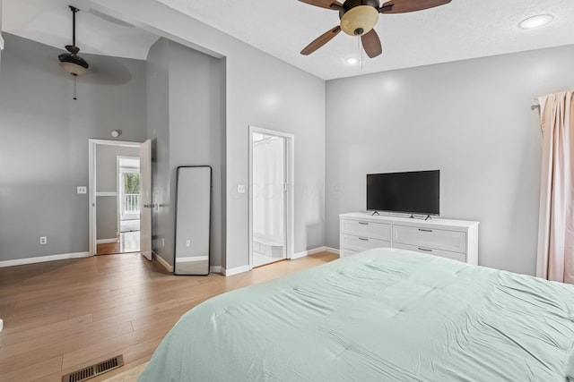 bedroom with ceiling fan, light wood finished floors, baseboards, a towering ceiling, and visible vents