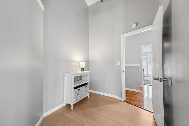 corridor with baseboards and light wood-style flooring