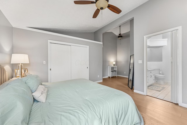 bedroom with ceiling fan, wood finished floors, ensuite bathroom, vaulted ceiling, and a closet