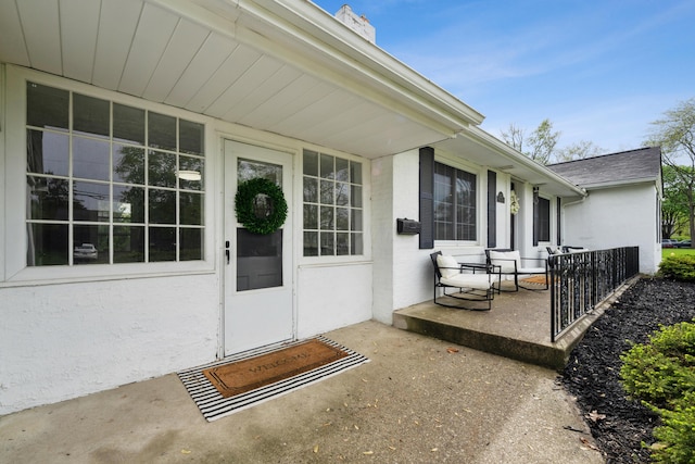 doorway to property with stucco siding and a chimney