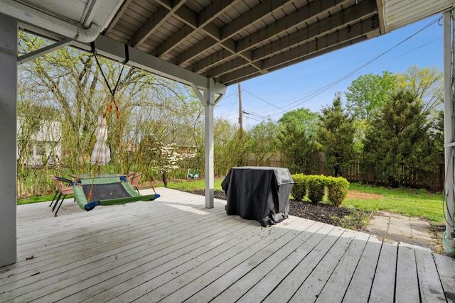 wooden terrace with a fenced backyard and area for grilling