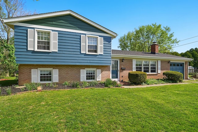 split level home featuring a front yard, a garage, brick siding, and a chimney