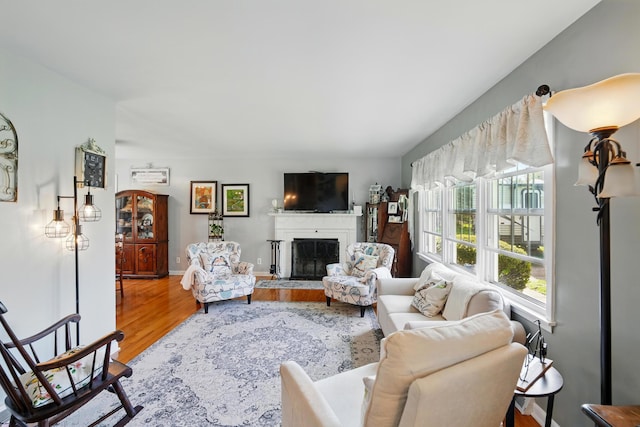 living area featuring a fireplace, wood finished floors, and baseboards