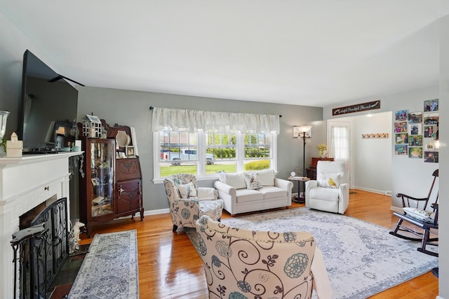 living room with a fireplace with flush hearth, wood finished floors, and baseboards