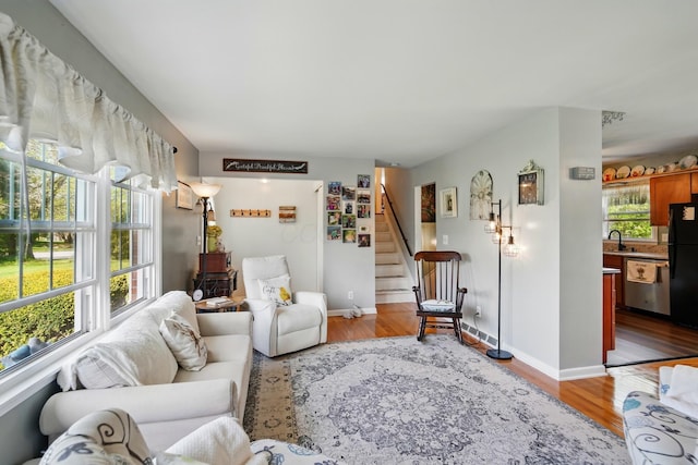 living room featuring baseboards, stairway, and light wood-type flooring