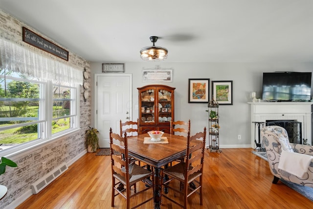 dining space featuring a brick fireplace, visible vents, baseboards, and light wood-type flooring