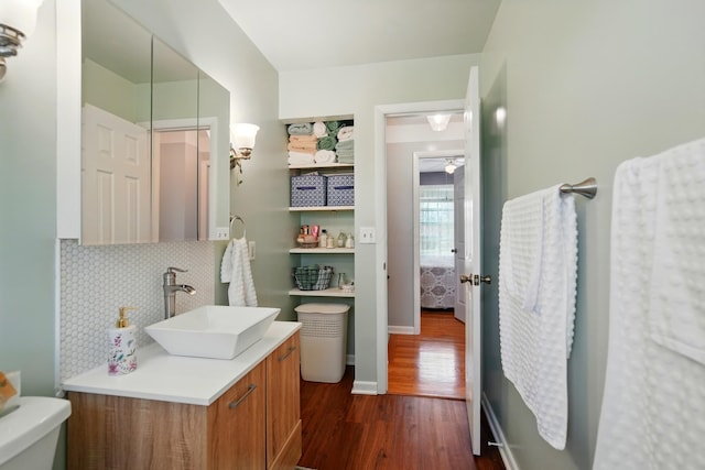 bathroom with vanity, ceiling fan, toilet, backsplash, and wood finished floors