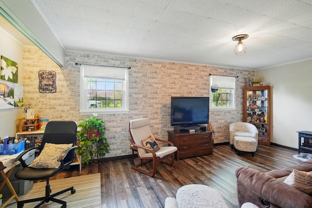 living room with a wood stove, brick wall, baseboards, ornamental molding, and wood finished floors