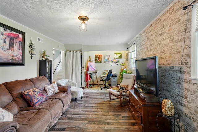 living room featuring visible vents, brick wall, ornamental molding, dark wood-type flooring, and stairs