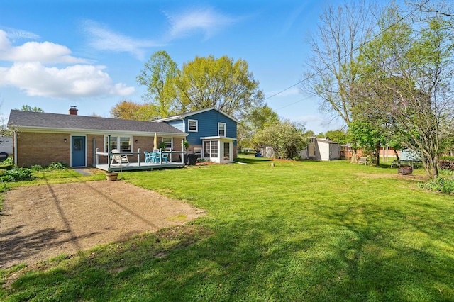 back of property featuring an outbuilding, a storage shed, a lawn, brick siding, and a deck