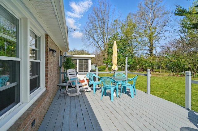 wooden deck featuring a yard, a sunroom, and outdoor dining area