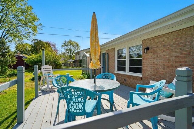 wooden terrace with fence, outdoor dining space, and a yard