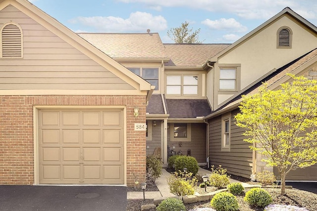 multi unit property featuring aphalt driveway, brick siding, and roof with shingles