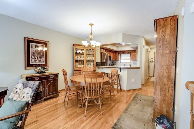 dining space featuring light wood-style floors and a notable chandelier