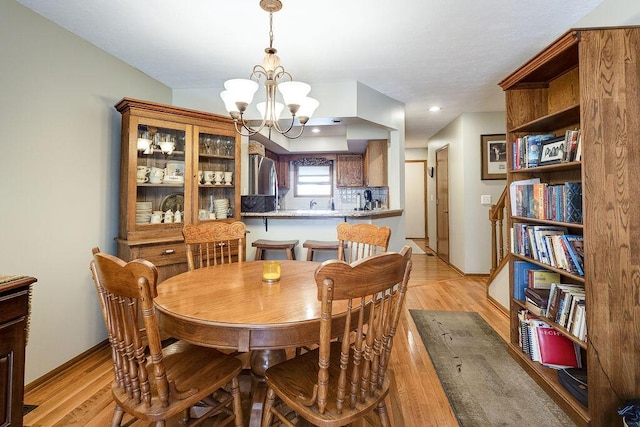 dining area with light wood-style floors, baseboards, and an inviting chandelier