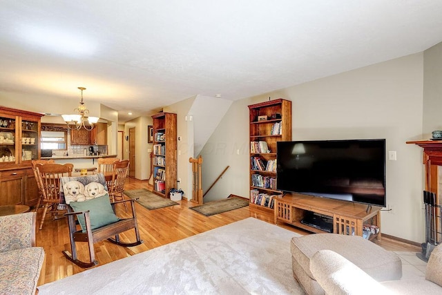 living room featuring baseboards, lofted ceiling, a chandelier, and light wood-type flooring