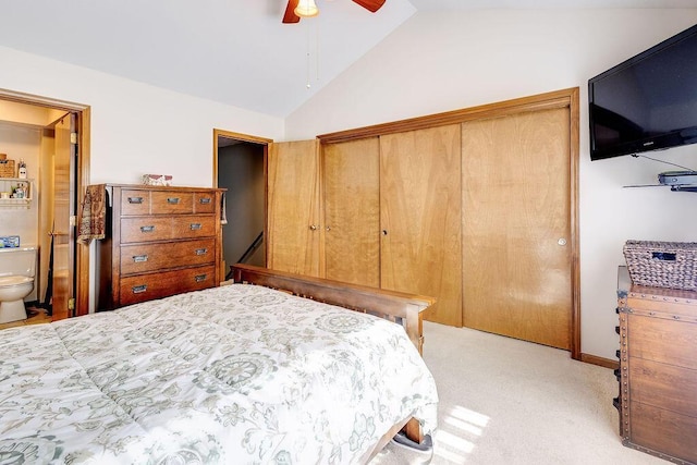 bedroom featuring vaulted ceiling, a ceiling fan, light carpet, ensuite bath, and a closet
