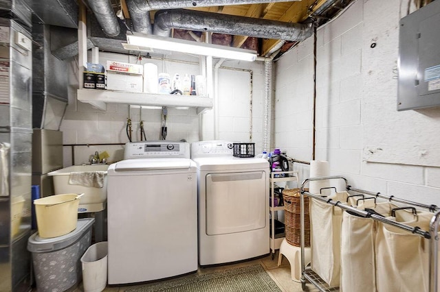 laundry area with concrete block wall, a sink, laundry area, and independent washer and dryer