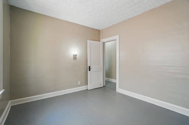 spare room featuring a textured ceiling, baseboards, and wood finished floors