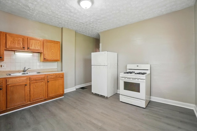 kitchen with a sink, light wood-style floors, white appliances, and a textured ceiling