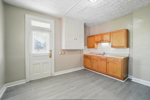kitchen featuring light countertops, baseboards, a sink, and light wood-type flooring