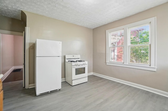 kitchen with baseboards, a textured ceiling, light wood-style flooring, and white appliances
