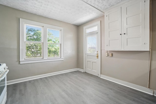 doorway to outside with baseboards, a textured ceiling, and wood finished floors