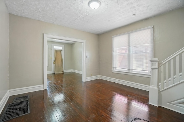 spare room with visible vents, a textured ceiling, wood-type flooring, and baseboards