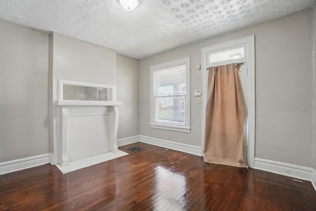 unfurnished dining area featuring wood-type flooring, a textured ceiling, baseboards, and visible vents