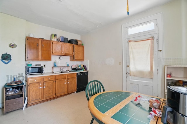 kitchen featuring brown cabinets, a sink, black dishwasher, stainless steel microwave, and backsplash