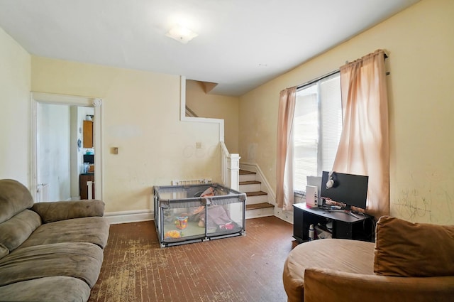 living area featuring baseboards, wood finished floors, and stairway
