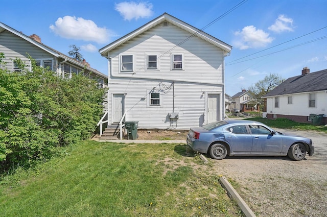 rear view of property featuring entry steps and a lawn