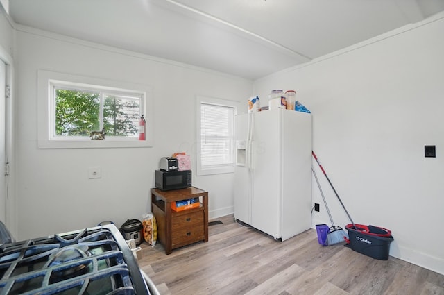 bedroom featuring light wood finished floors and white fridge with ice dispenser