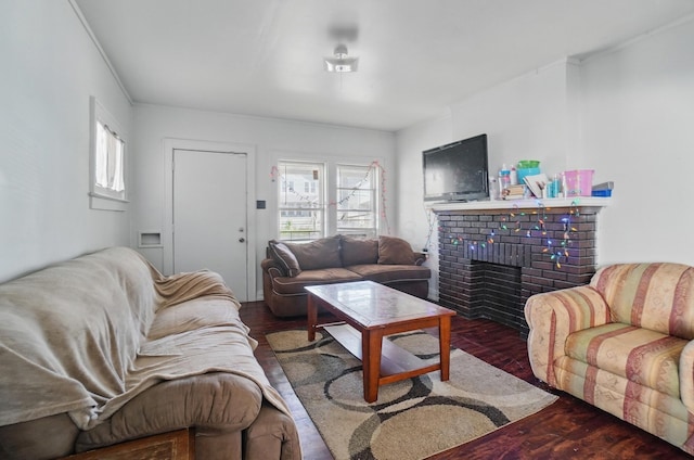 living room with a brick fireplace and wood finished floors