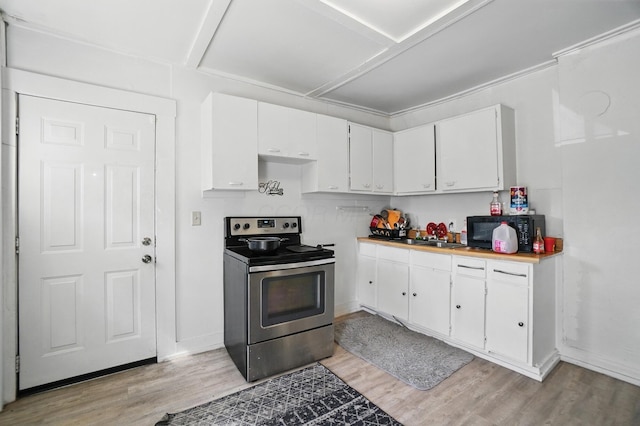 kitchen featuring black microwave, stainless steel range with electric stovetop, light countertops, light wood-style floors, and white cabinetry