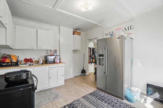 kitchen featuring light countertops, stainless steel refrigerator with ice dispenser, white cabinetry, and electric range