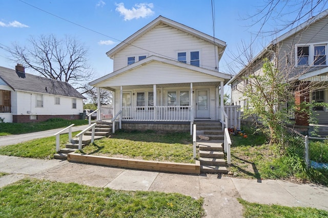 view of front of house with fence, covered porch, and a front lawn