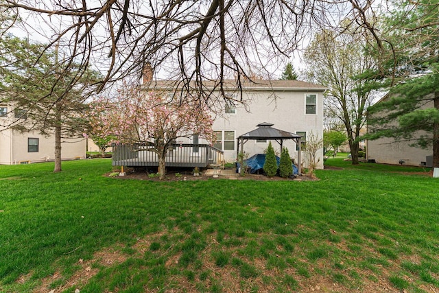 rear view of house with stucco siding, a gazebo, a yard, and a deck