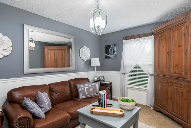 living area with wainscoting, light carpet, a chandelier, and a textured ceiling