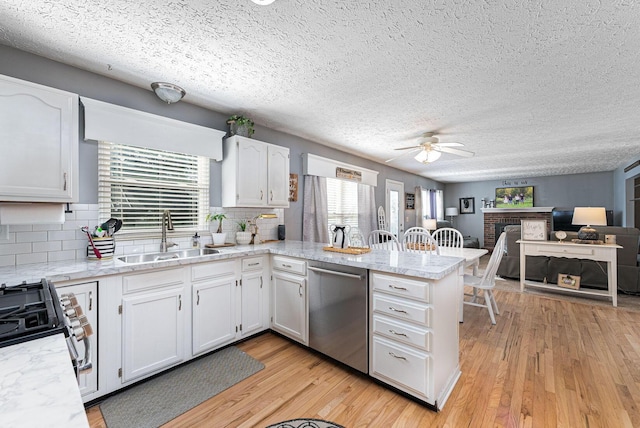 kitchen featuring a ceiling fan, a sink, stainless steel appliances, a peninsula, and white cabinetry